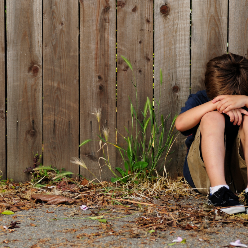 Child sitting alone outdoors during summer